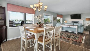 A spacious living area with a dining table, chairs, a sofa, and a TV. - Gorgeous sunset views looking over the waterway! 4BR/2.5Bath (Wrightsville Beach)
