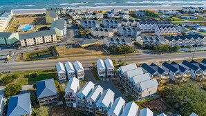A coastal residential area with multiple houses, a road, and a beach. - Melon Camp - Dive into Fun with Pool Access! (Surf City)