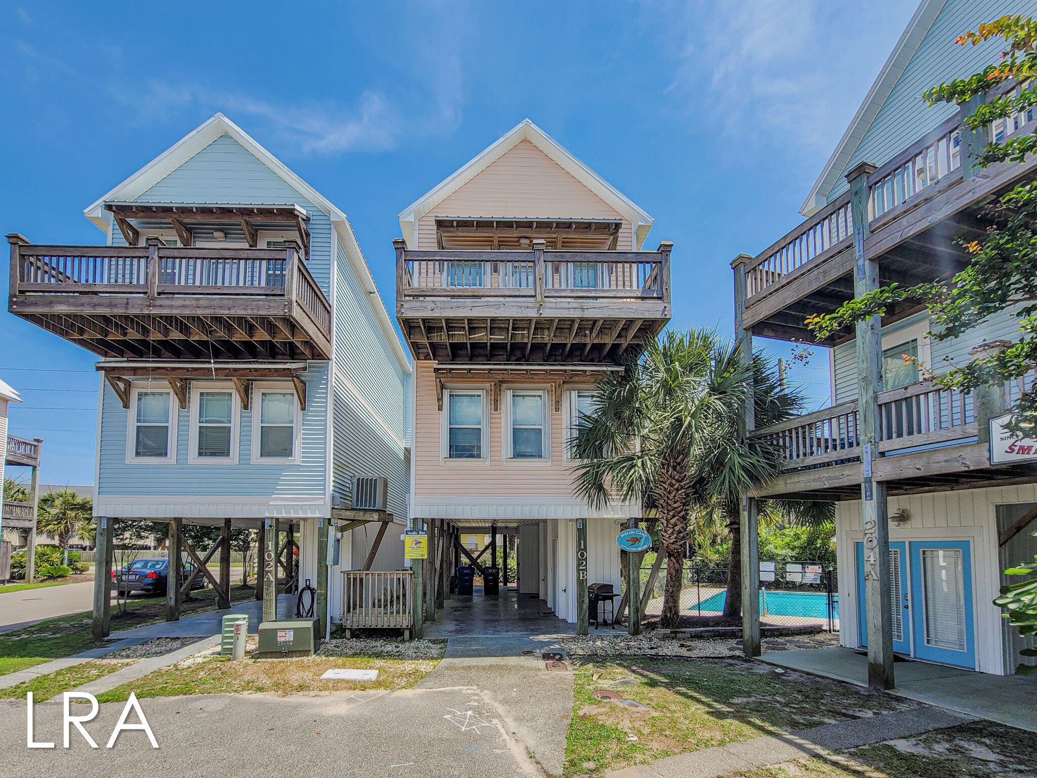 A row of two-story buildings with balconies, a small pool, and a sign indicating a restaurant.