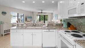 Una cocina moderna con armarios blancos, encimera de granito, microondas integrado y estufa.
