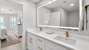 A modern bathroom with white cabinetry, gold handles, a large mirror, and a unique bowl-shaped sink. - Gulf Front Condo in Gated Complex and Seasonal Beach Service (Destin)