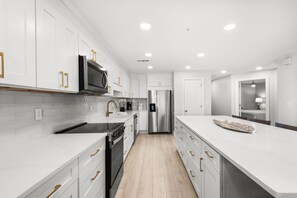 A modern kitchen with white cabinetry, stainless steel appliances, and a central island.