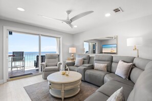 A modern living room with a grey sofa, a round coffee table, and a ceiling fan.