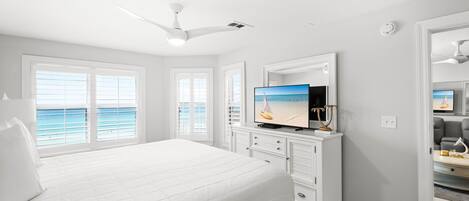 Quarto com uma cama grande, televisão e vista para o mar.