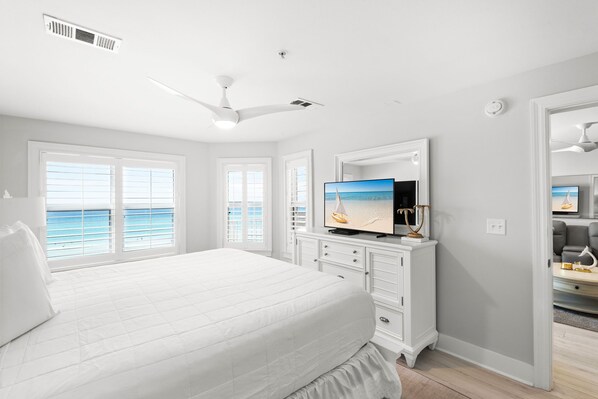 Un dormitorio con una cama grande, televisión y vista al mar.