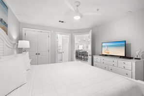 A bedroom with a bed, a television, a dresser, and a ceiling fan.