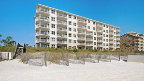 A multi-story hotel with balconies, located near a sandy beach. - Gulf Front Condo in Gated Complex and Seasonal Beach Service (Destin)