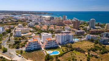 A coastal cityscape with high-rise buildings, a marina, and a swimming pool.