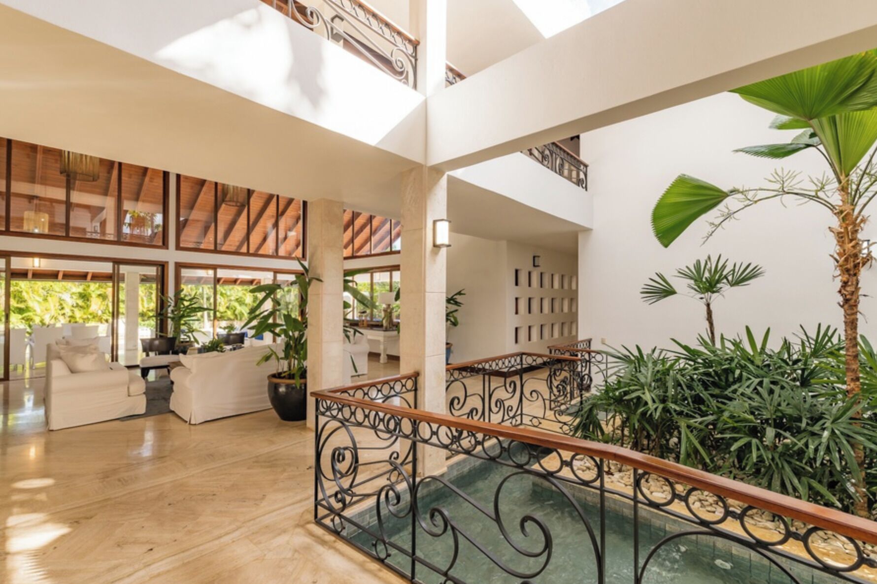 A spacious indoor area with a wooden ceiling, a pool, and potted plants.