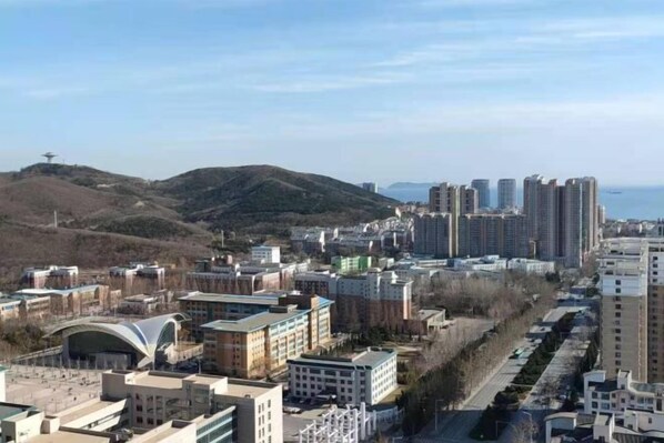 A cityscape with modern buildings, a prominent curved structure, and a hilly background.
