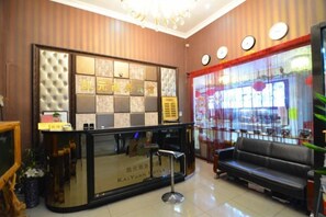 Un hall d’hôtel comprenant un comptoir d’accueil, un espace salon et une grande fenêtre avec des rideaux.