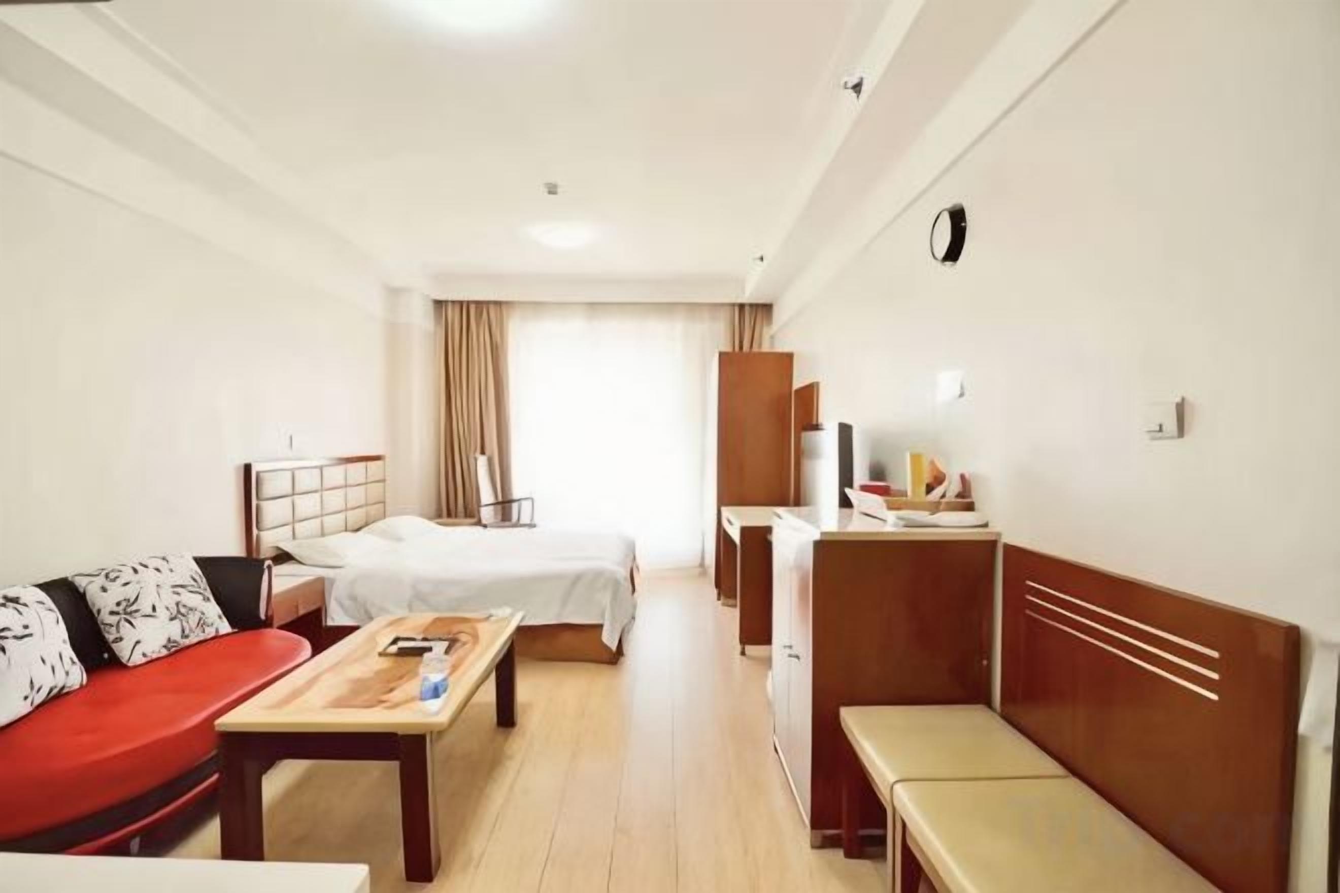 A hotel room with a bed, a sofa, a desk, and a small table.