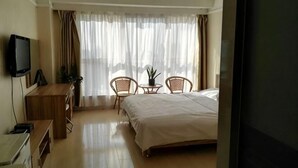 Hotellihuone, jossa on sänky, televisio, työpöytä ja tuoli.