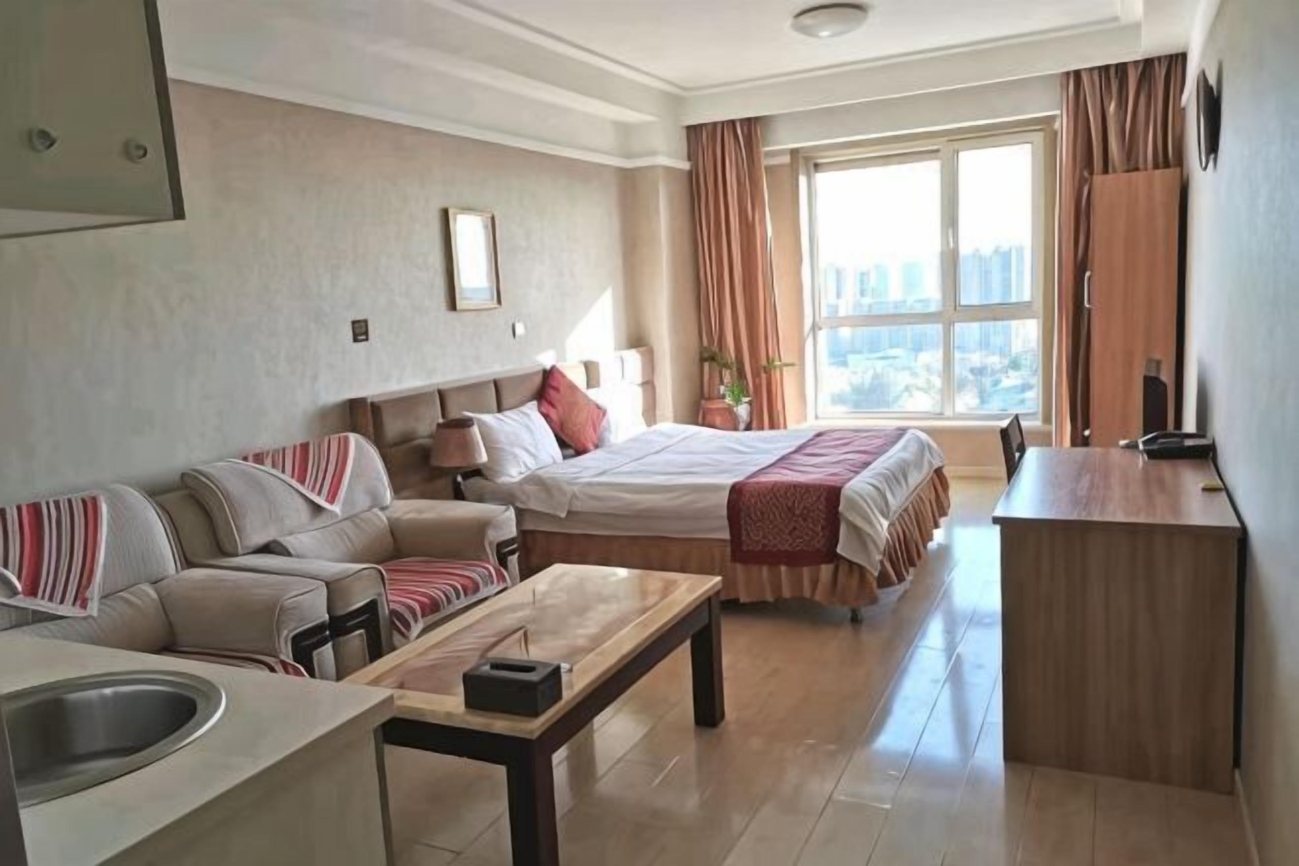 Habitación de hotel con cama, sofá, escritorio y vista a la ciudad.