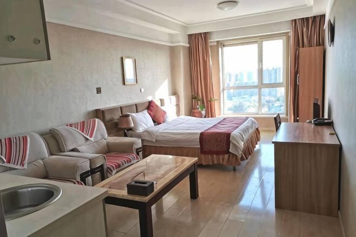 Habitación de hotel con cama, sofá, escritorio y vista a la ciudad.