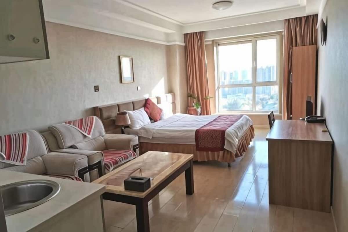 Habitación de hotel con cama, sofá, escritorio y vista a la ciudad.