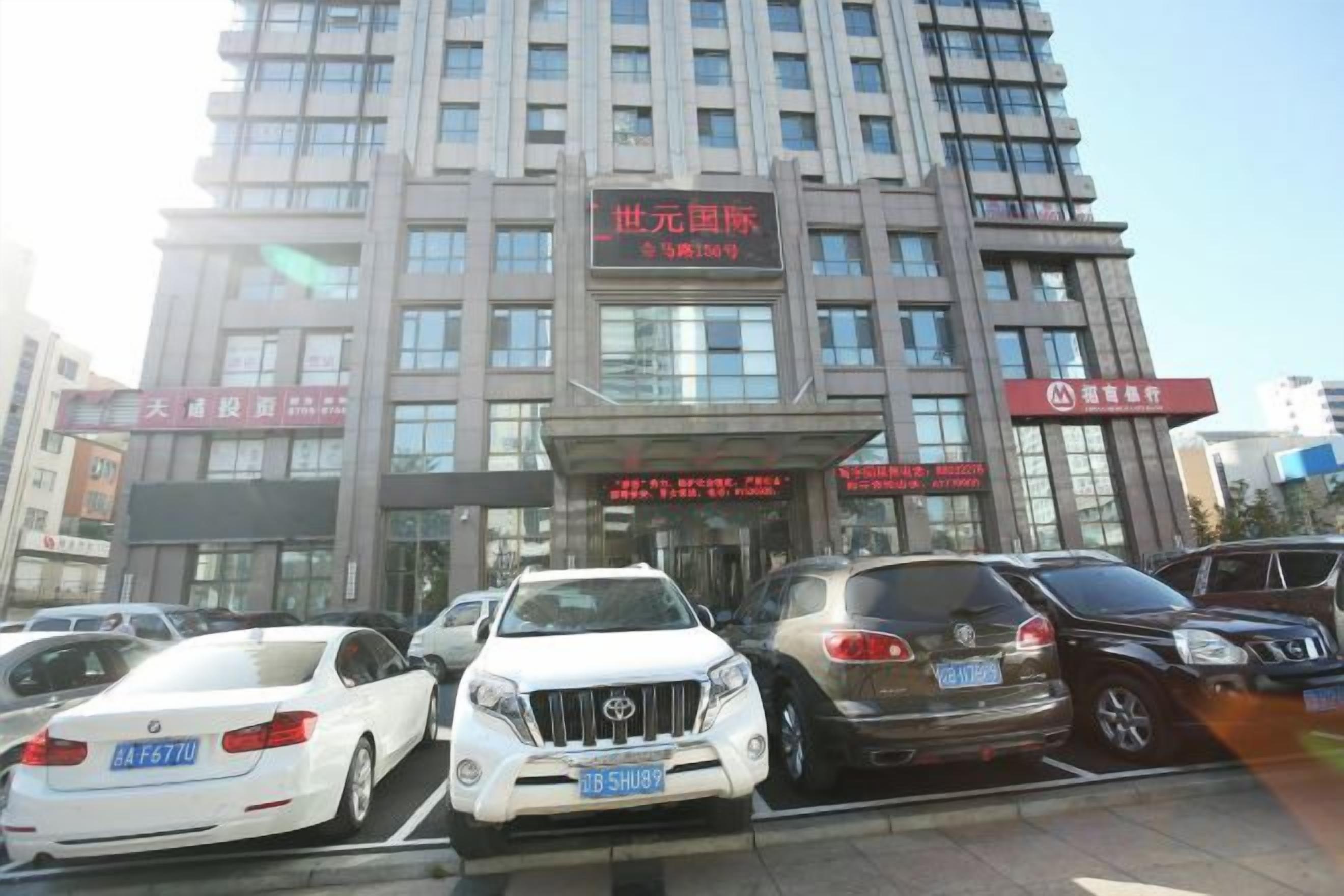 Un hotel de varios pisos con una entrada destacada y varios coches estacionados al frente.