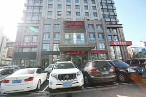 A multi-story hotel with a prominent entrance and several parked cars in front.