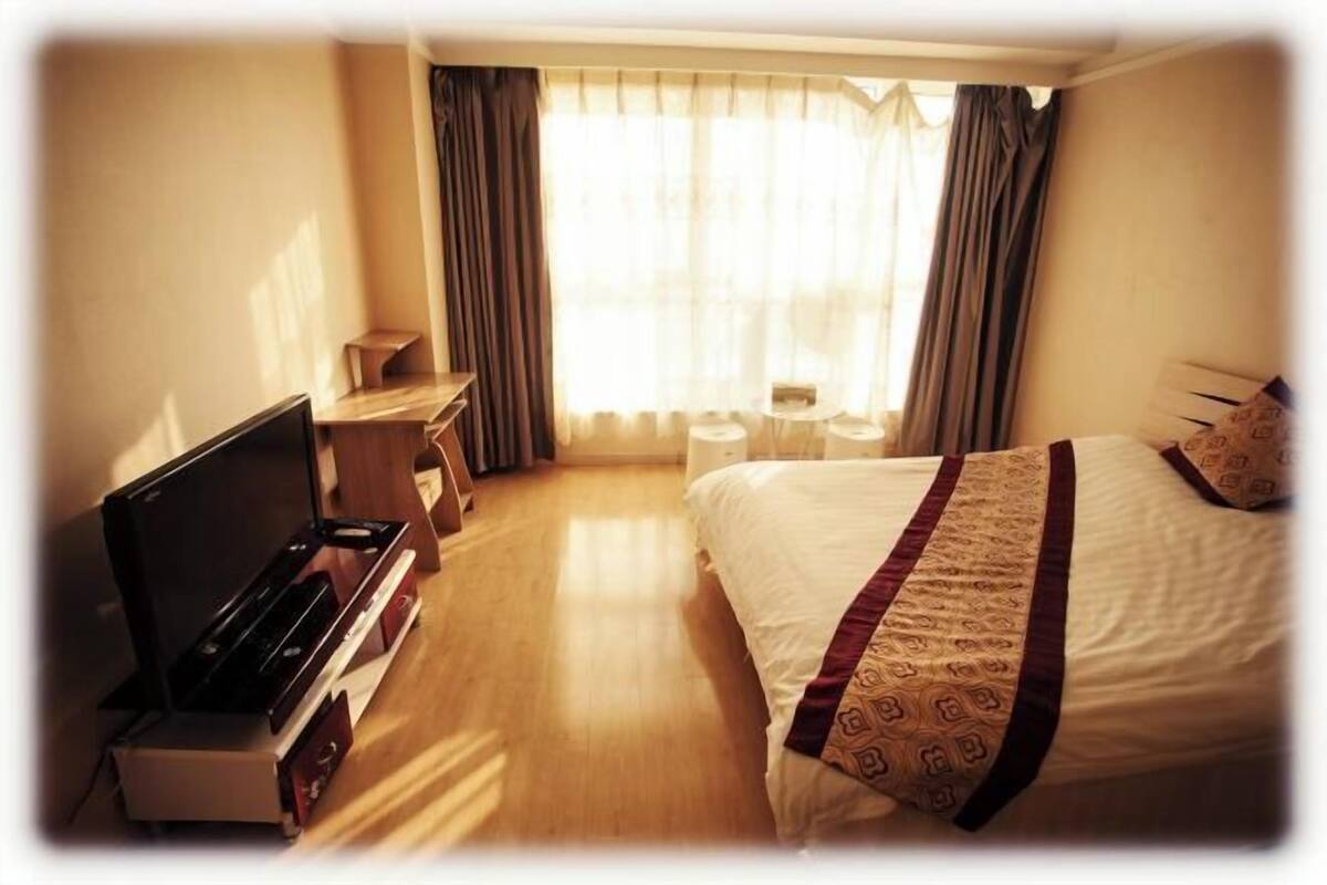Una habitación de hotel con cama, escritorio, televisión y una pequeña mesa.