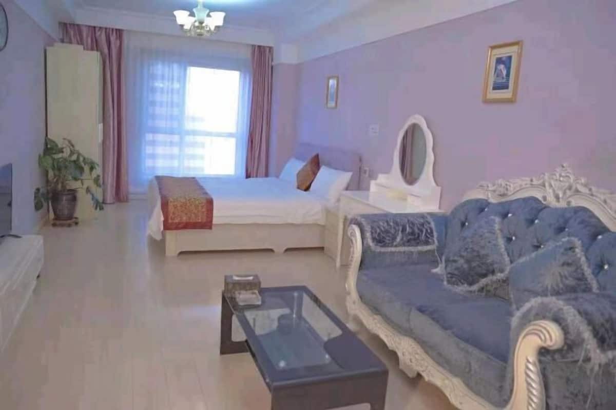 Un dormitorio con cama, mesita de noche, espejo, sofá y mesa de centro.