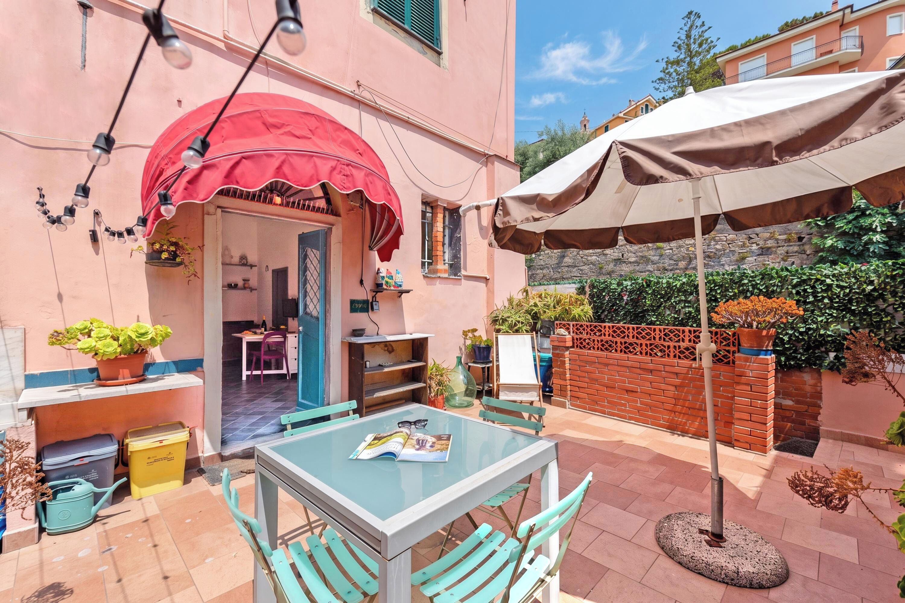 A patio with a table, chairs, a red umbrella, and a brown umbrella.