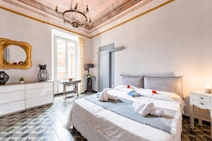 Habitación de hotel con cama, escritorio, silla, espejo y candelabro.