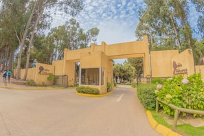 A building entrance with a sign, a paved pathway, and a small garden area.