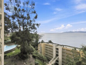 Un immeuble résidentiel offrant une vue sur une vaste étendue d’eau, une piscine et un ciel dégagé.