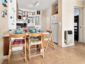 Cocina compacta con una mesa de comedor para cuatro personas, un refrigerador y un microondas.