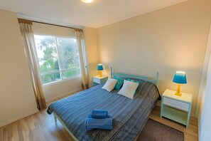 A bedroom with a bed, two bedside tables, a window, and a view of greenery outside. - Oceana Suites Bahía Pelicanos (Puchuncavi)