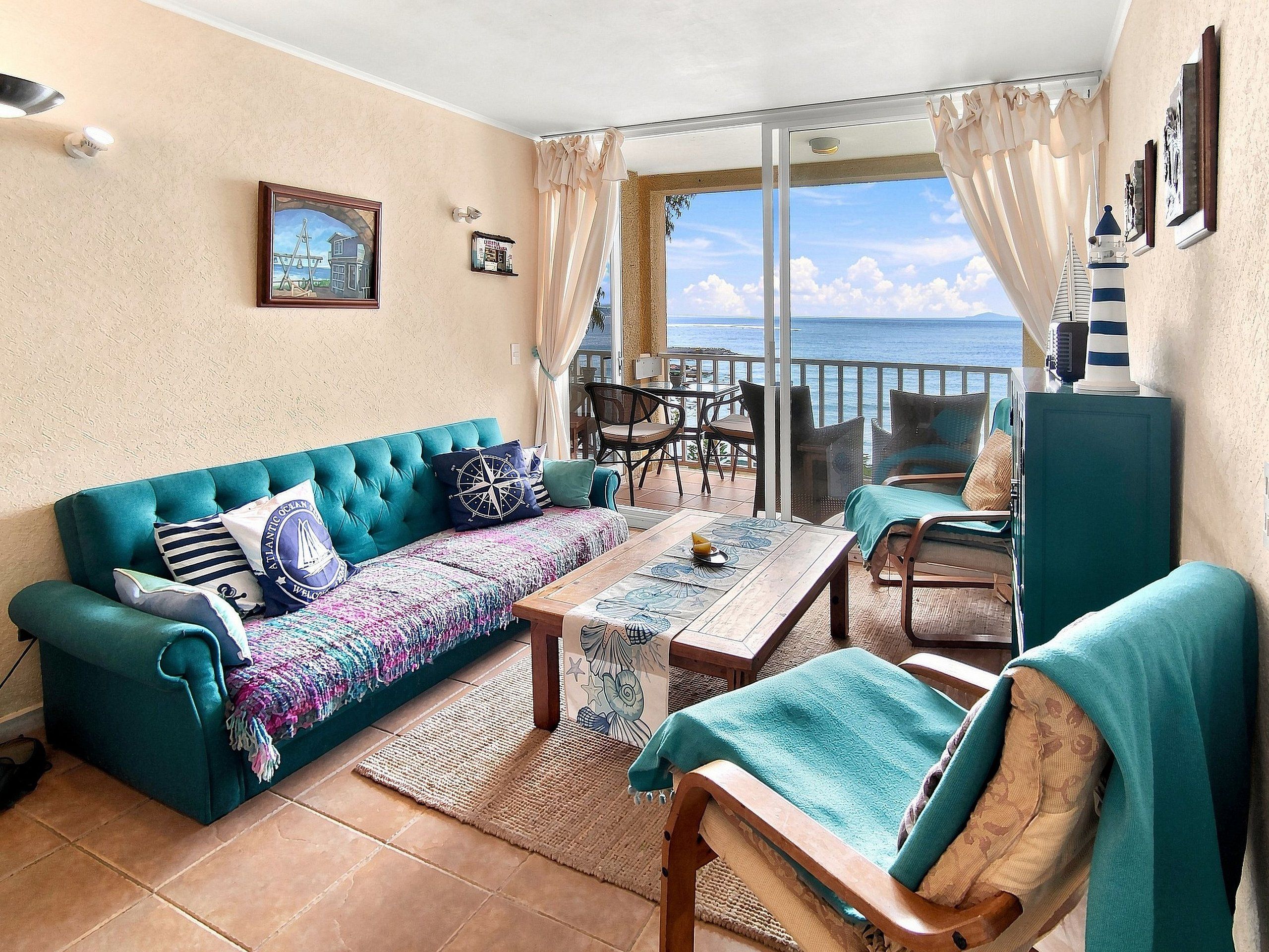 A cozy living area with a sofa, a coffee table, and a view of the sea.