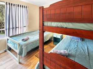 A room with two bunk beds, a striped curtain, and a small bedside table.