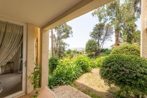 Een overdekt terras met uitzicht op een tuin en bomen.
