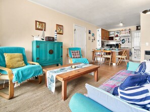 A living room with a teal armchair, a wooden coffee table, and a sofa with striped cushions. - Oceana Suites Bahía Pelicanos (Puchuncavi)
