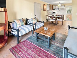 A living room with two sofas, a coffee table, and a dining area with chairs and a table.