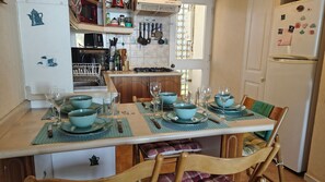 A kitchen with a dining table set for four, a refrigerator, and various kitchen appliances. - Oceana Suites Bahía Pelicanos (Puchuncavi)