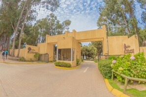 A building entrance with a sign, a paved pathway, and a small garden area.