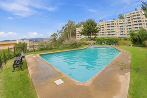Une piscine rectangulaire bordée de béton, entourée d’une pelouse et d’une clôture en bois.