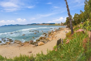 A beach with a rocky shoreline, a clear sky, and distant mountains. - Oceana Suites Bahía Pelicanos (Puchuncavi)