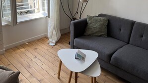 Un salon moderne avec un canapé gris, une table basse blanche et un lampadaire.