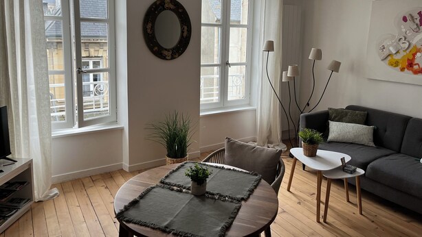 Un salon avec une table ronde, un canapé et un téléviseur.