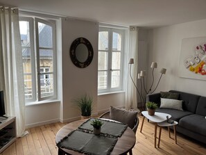 Una sala de estar con una mesa redonda, un sofá y un televisor.