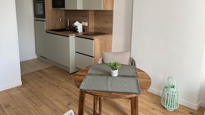 Une cuisine moderne agrémentée d’éléments en bois, un coin repas avec une table ronde et une petite plante en pot.