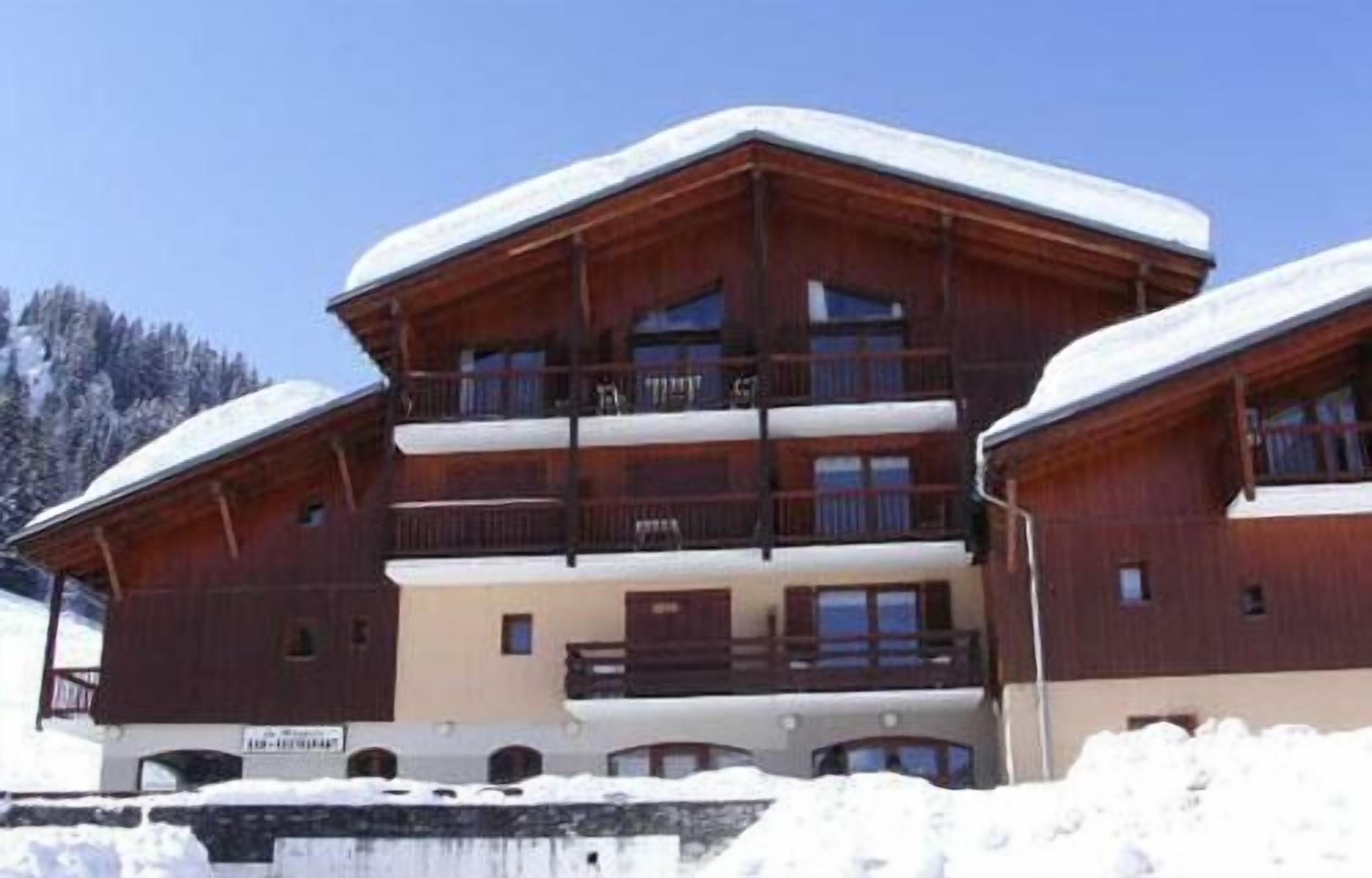 Um edifício de madeira com várias andares e varandas, rodeado por neve.