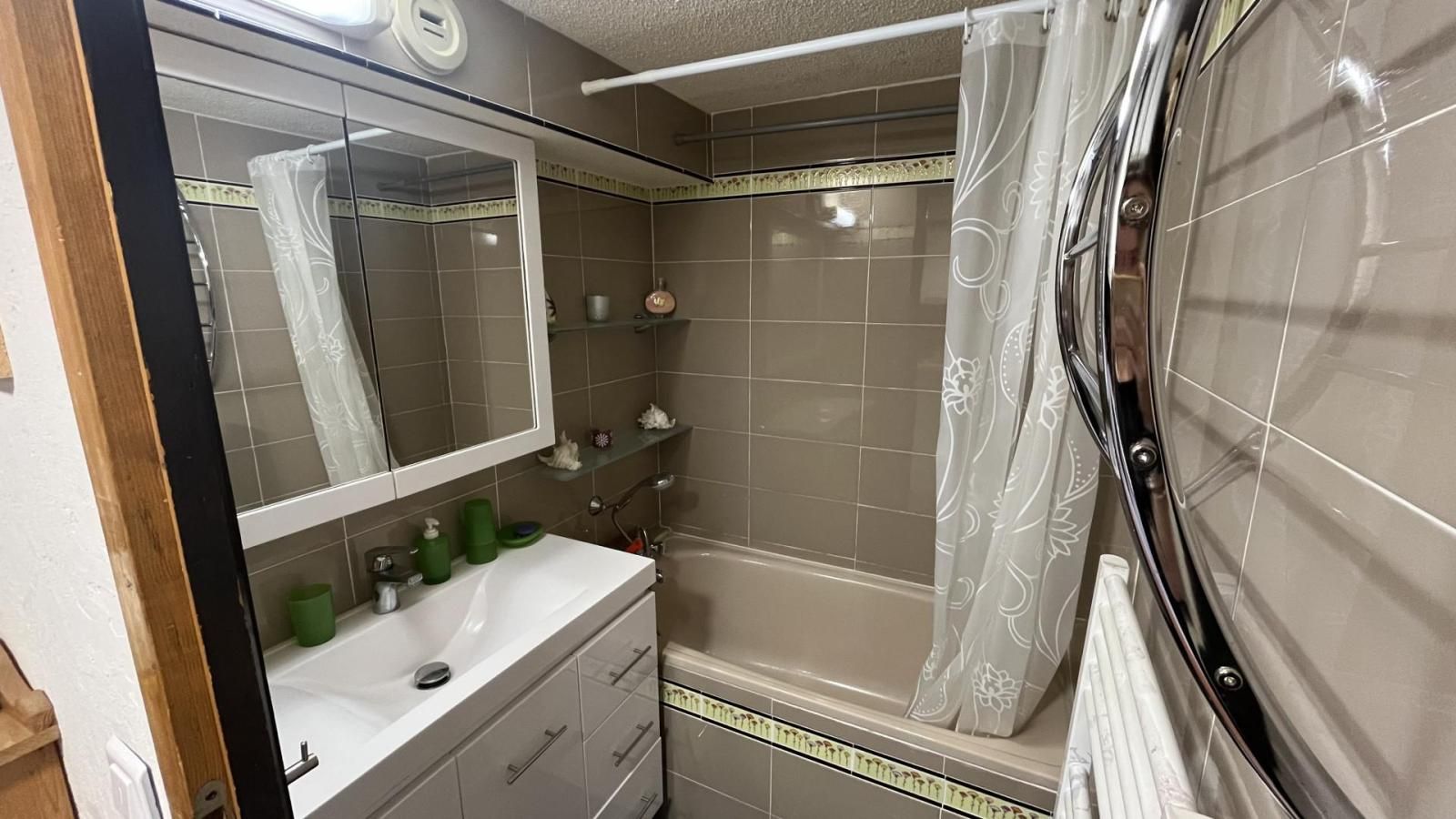 Un baño con ducha, lavamanos y espejo.