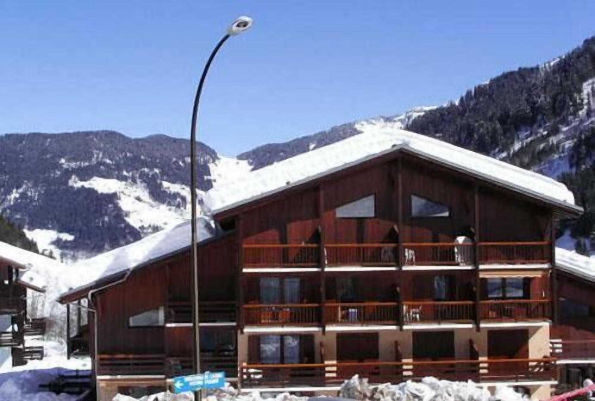 Um edifício de madeira com várias varandas, rodeado por montanhas cobertas de neve.