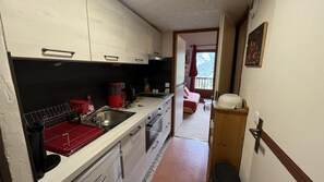 Een kleine keuken met een spoelbak, een koffiezetapparaat en een afwassysteem.