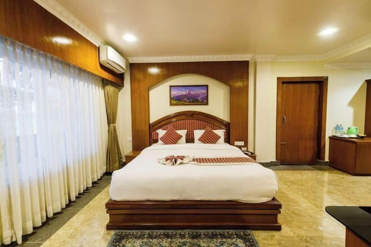Una habitación de hotel con una cama grande, un cabecero de madera, un cuadro en la pared y una puerta.