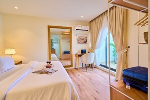 A hotel room with a bed, a desk, a chair, a suitcase, and a window with curtains.