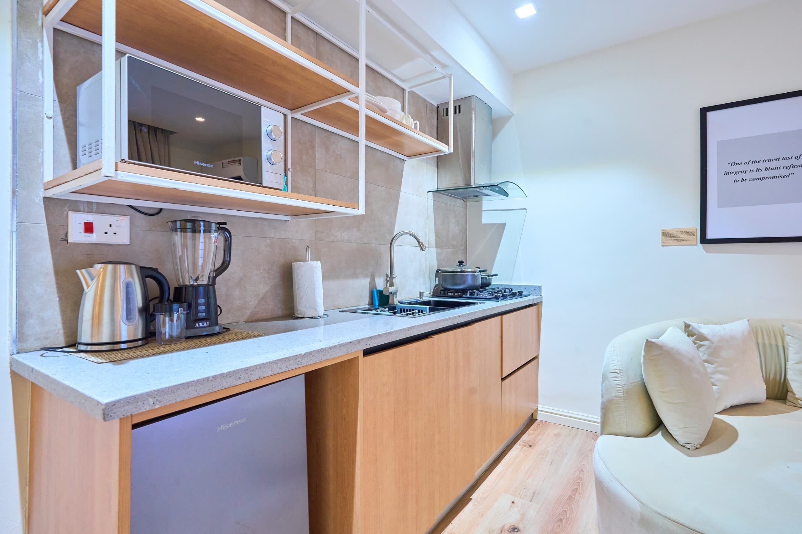 A modern kitchen with a built-in dishwasher, a kettle, a blender, and a stove.
